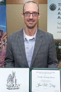 portrait of a man with glasses holding award