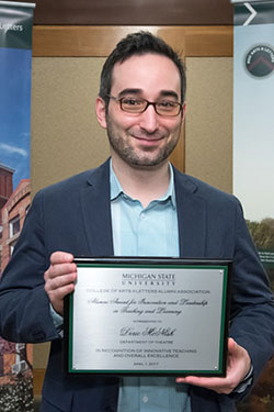 portrait of a man with glasses holding award