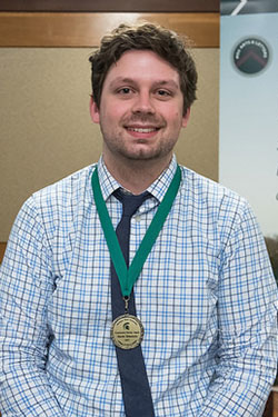portrait of a man with brown hair wearing award medal