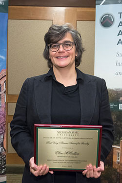 portrait of a woman with glasses holding award